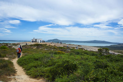 Rear view of people walking on mountain against sky