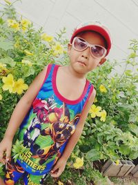 Portrait of boy with eating lollypop standing against plants