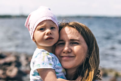 Portrait of mother with baby against water