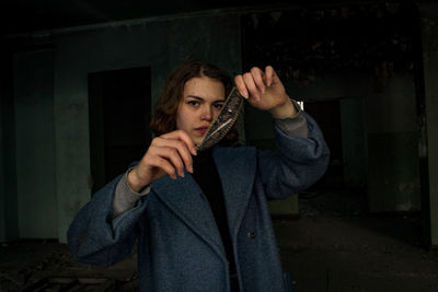 Portrait of woman standing against wall at night