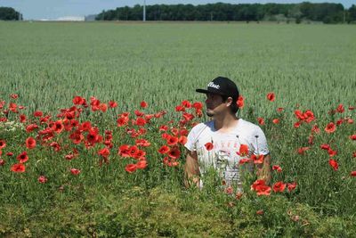 Young woman standing by poppy field