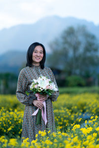 Portrait of a smiling young woman standing on field