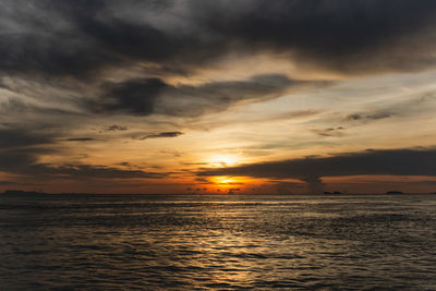 Scenic view of sea against dramatic sky during sunset