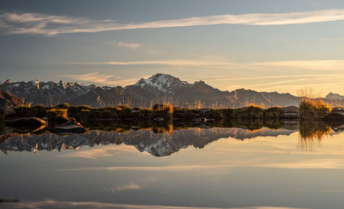 Scenic view of lake by mountains against sky during sunset