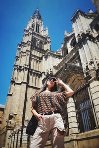 Low angle view of woman by building against sky