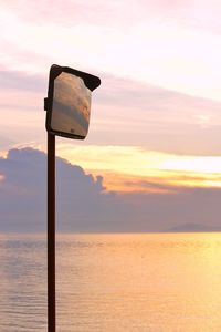 Information sign by sea against sky during sunset