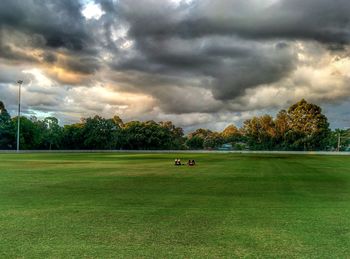 Scenic view of grassy field against cloudy sky