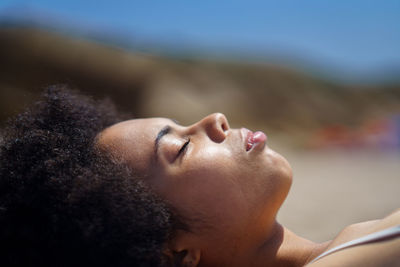 Woman with afro hairstyle lying on beach