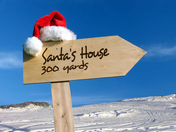 Information sign on snow covered landscape against sky