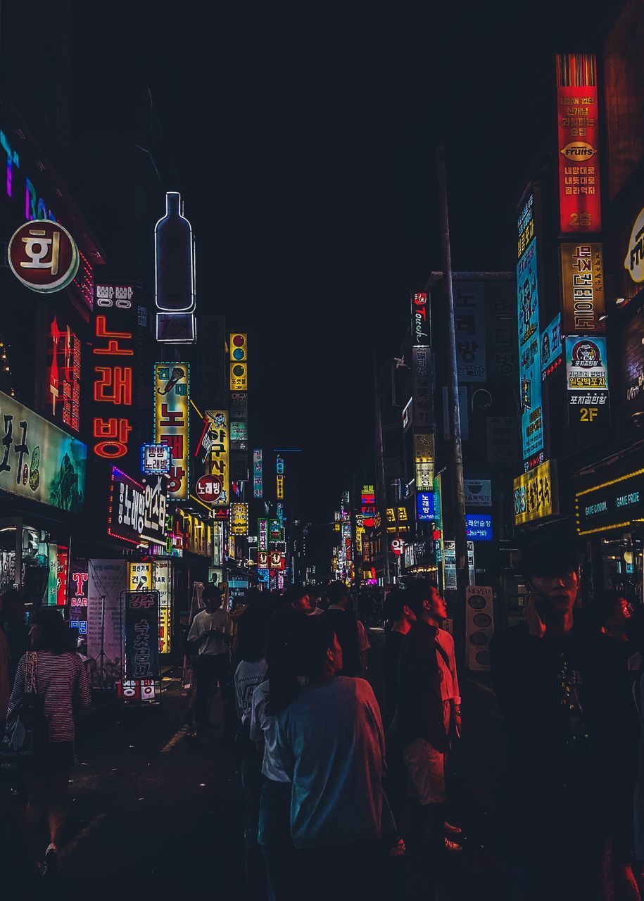 PEOPLE AT ILLUMINATED CITY STREET AT NIGHT