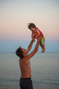 Father and son standing on beach against clear sky