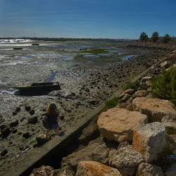 Rear view of woman standing on beach against clear sky