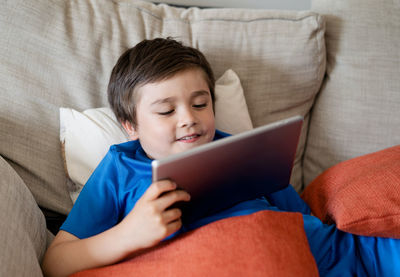 Boy using mobile phone on sofa