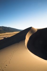 Sand dunes in desert against clear sky