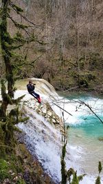 Man with umbrella on river in forest