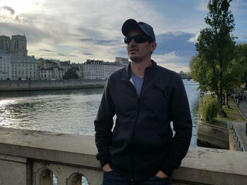 Portrait of young man standing in city against sky