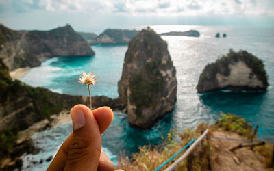 Person holding rock in sea against sky