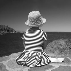 Rear view of child looking at sea against clear sky