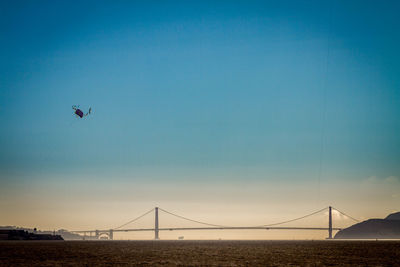 View of suspension bridge over bay against blue sky