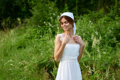 Young woman standing against plants