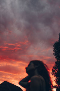 Low angle view of silhouette woman standing against sky during sunset