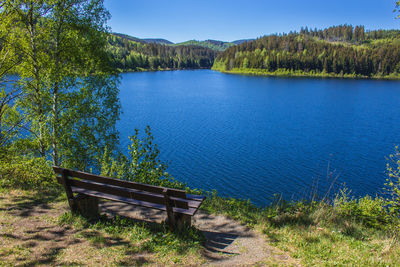 Scenic view of lake by trees against blue sky