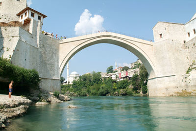 Arch bridge over river against buildings