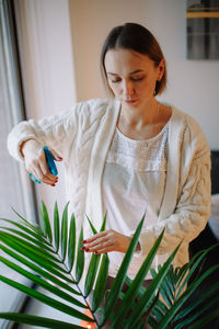 Woman watering plant at home