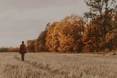 Rear view of person walking on field during autumn