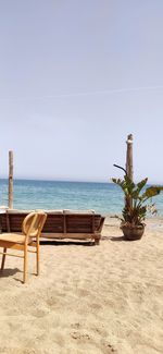 Chair on beach against sky