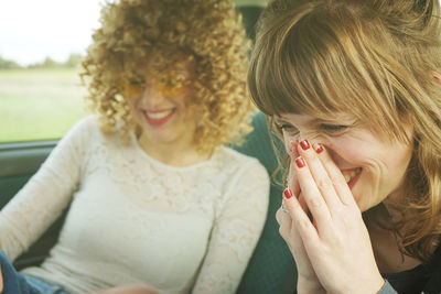 Cheerful female friends sitting in car