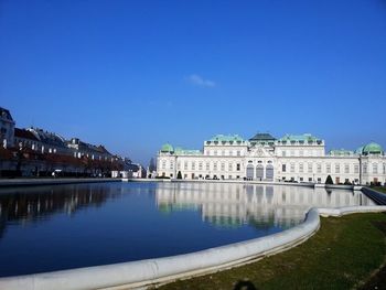 Buildings at waterfront against blue sky