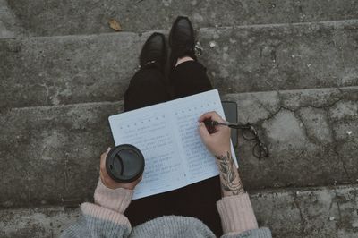 Low section of woman sitting on book against wall