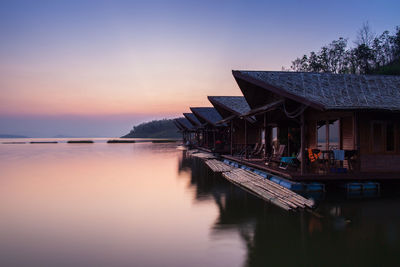 View of swimming pool by building against sky during sunset