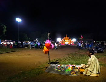 People sitting at illuminated city against sky at night