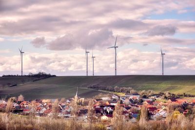 Village with wind mills against sky