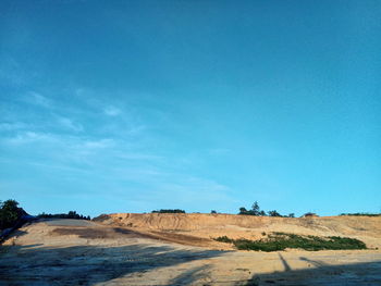 Scenic view of road by land against blue sky