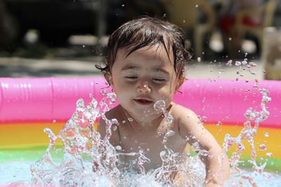 Cute boy splashing water in swimming pool
