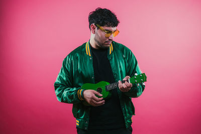 Portrait of young man standing against yellow background