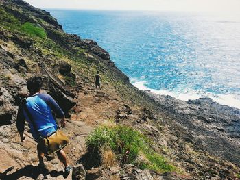 High angle view of men moving down from mountain against sea