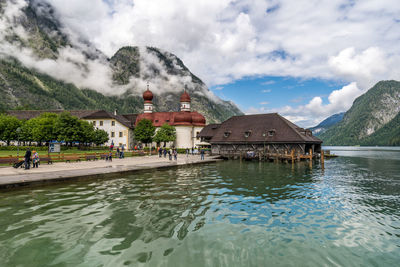 Buildings at waterfront against cloudy sky