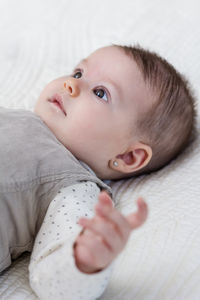 Portrait of cute baby lying on bed at home
