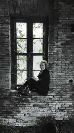 Portrait of woman sitting in abandoned window
