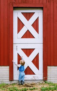 Boy standing by red door