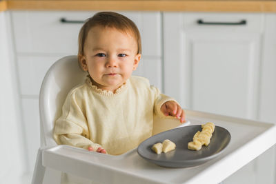 Portrait of cute baby boy eating food at home