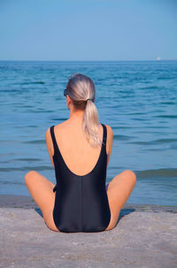 Rear view of woman at sea shore against sky