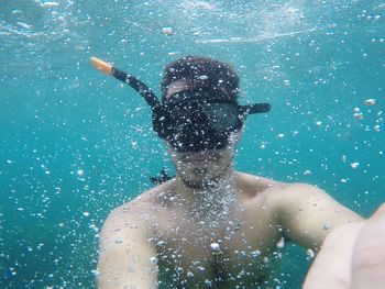 Portrait of shirtless man swimming in sea