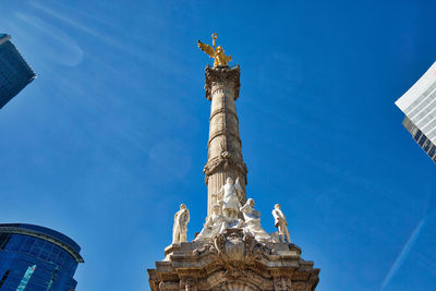 Low angle view of statue by historic building against sky