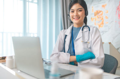 Smiling young woman using mobile phone at table