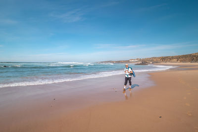 Rear view of woman walking at beach against sky